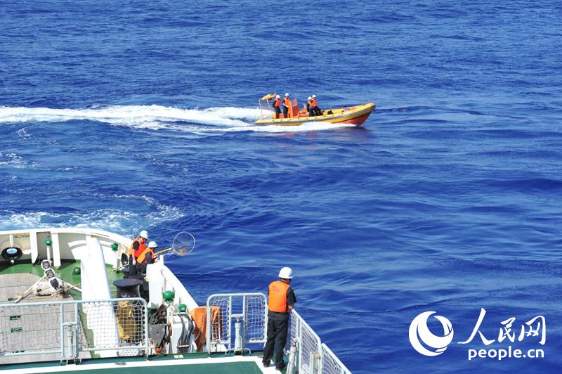 4月1日，“海巡01”在澳方今日公布的重點搜尋片區進行疑似物打撈、排除。圖為海巡01船載高速救生艇協同打撈組工作人員在后甲板等待打撈疑似漂浮物。張馳攝